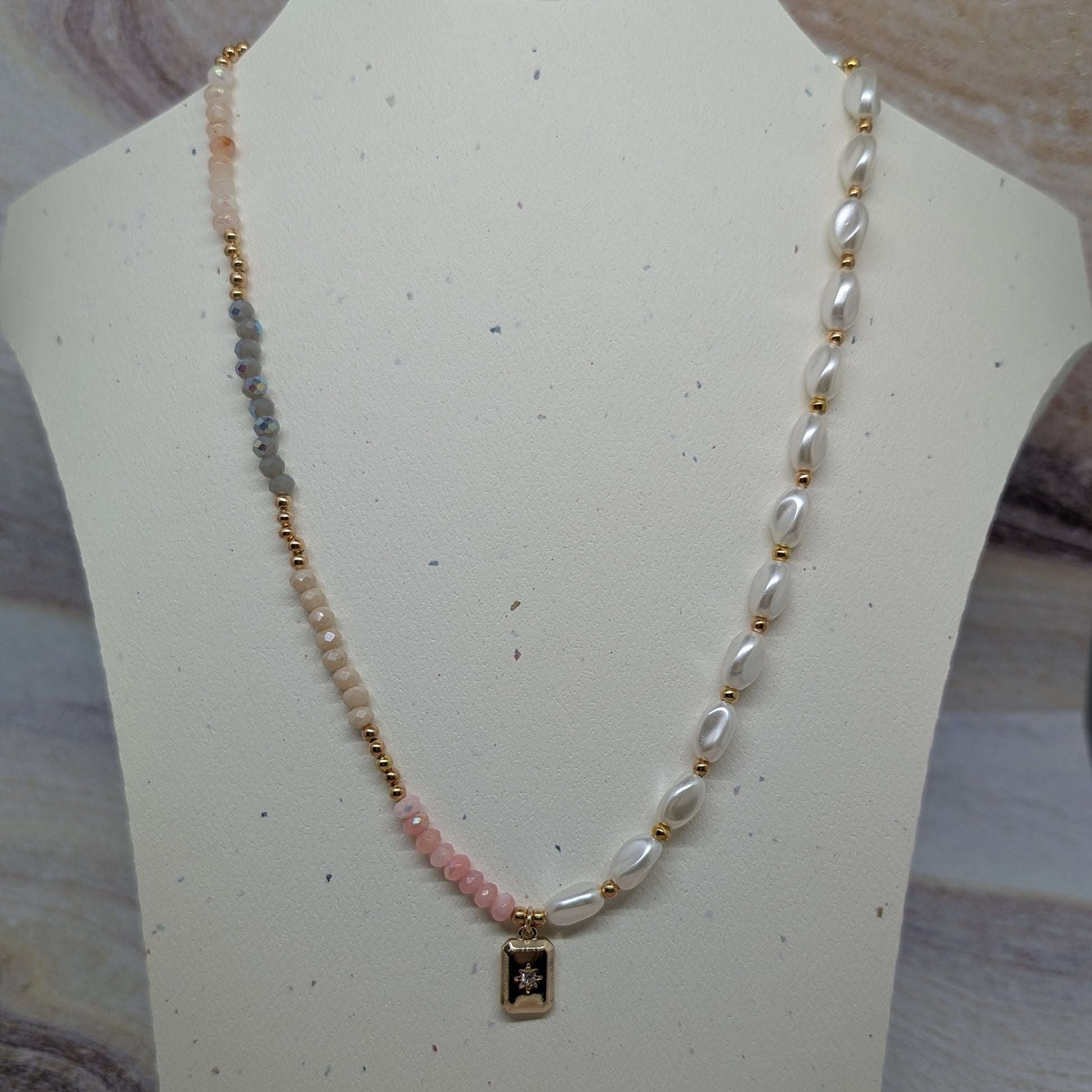 Necklace with pearls and a small pendant on a mannequin bust.