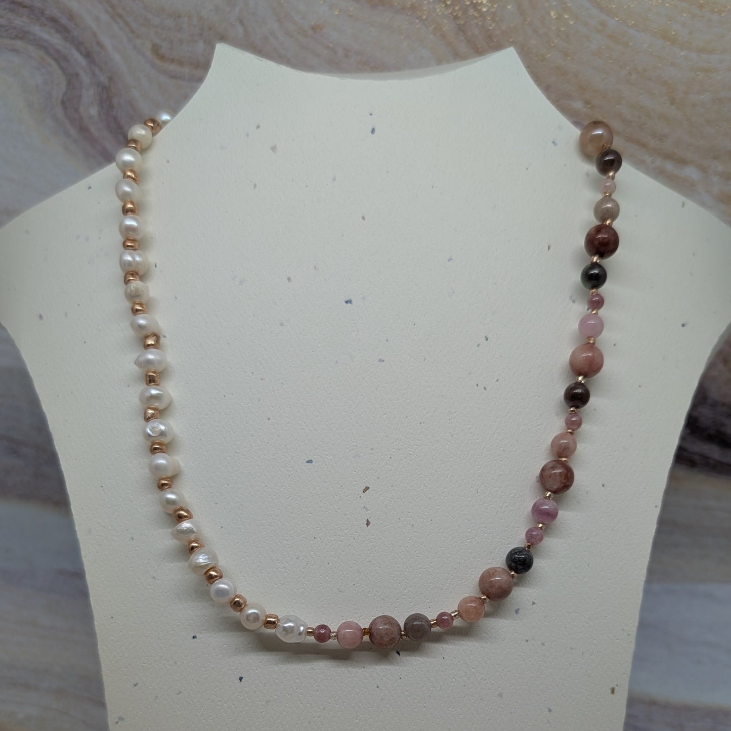 Necklace with multicolored beads on a white mannequin bust against a marble background