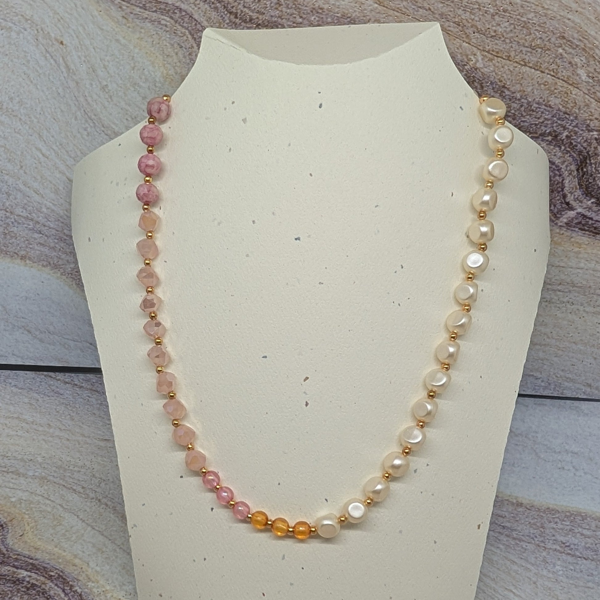 Necklace with multicolored beads on a mannequin bust against a marble background