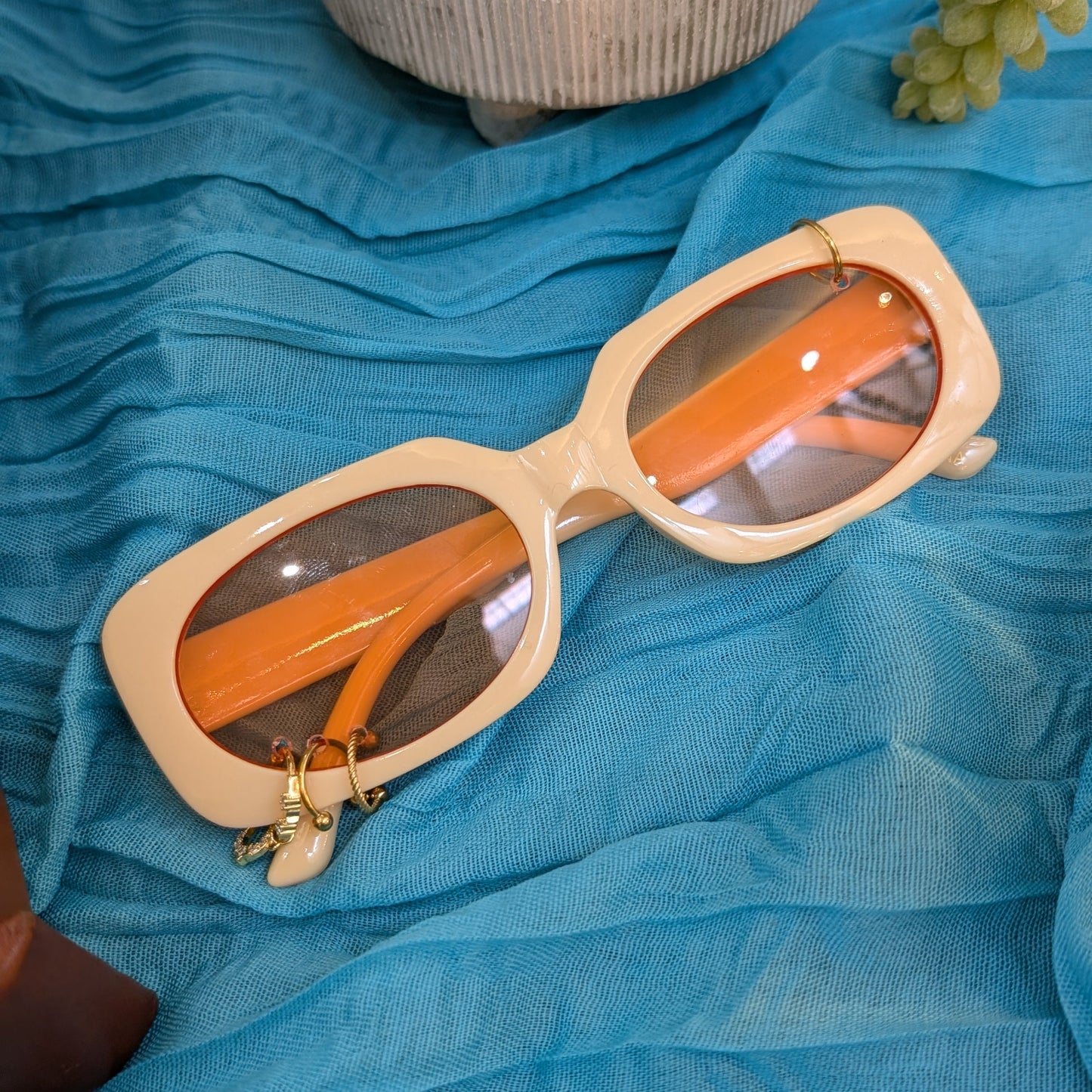 Sunglasses with orange lenses and beige frame on a blue fabric background