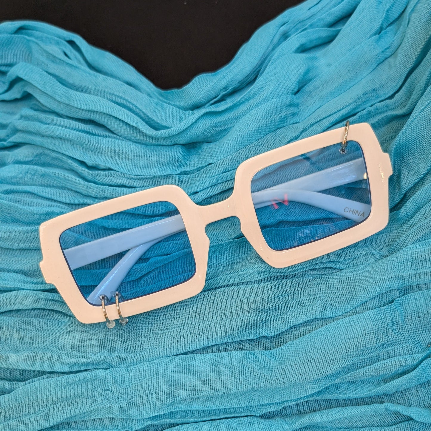 Beige sunglasses with reflective lenses on a blue fabric background