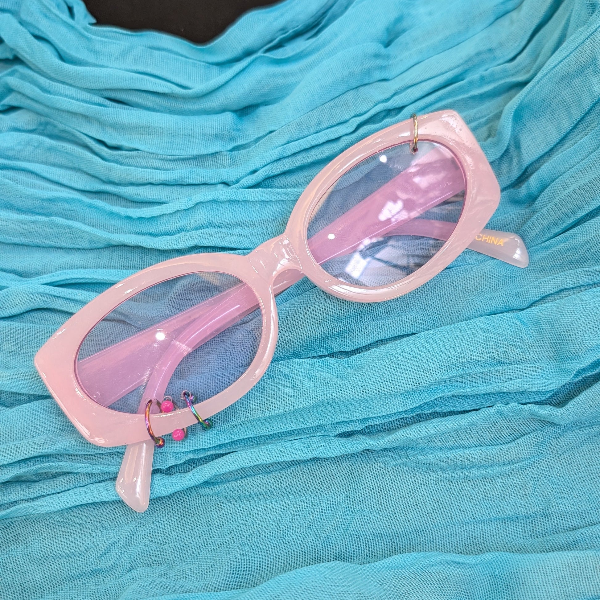 Pink sunglasses on a blue textured surface