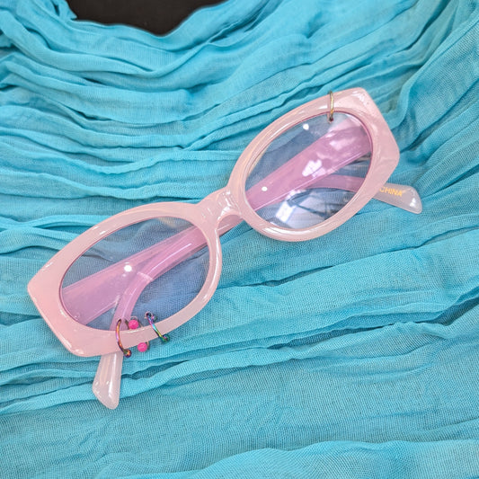Pink sunglasses on a blue textured surface