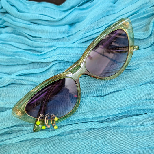 Gold-framed sunglasses with reflective lenses on a blue fabric background