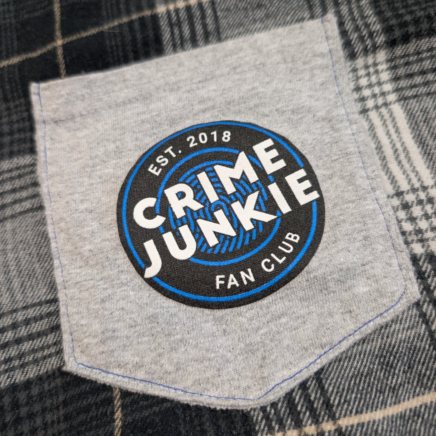 Patch on a plaid shirt with 'Crime Junkie Fan Club' text