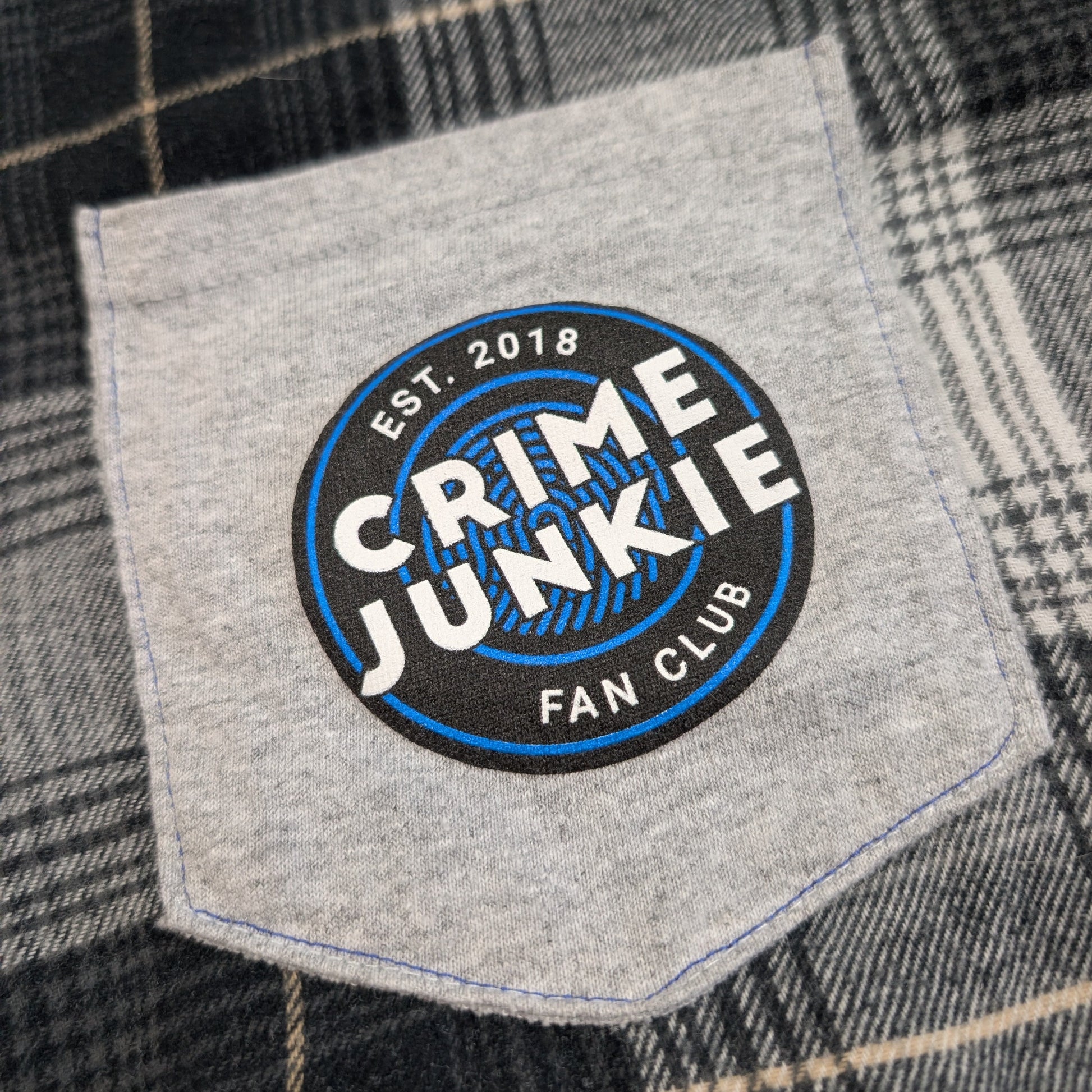 Patch on a plaid shirt with 'Crime Junkie Fan Club' text