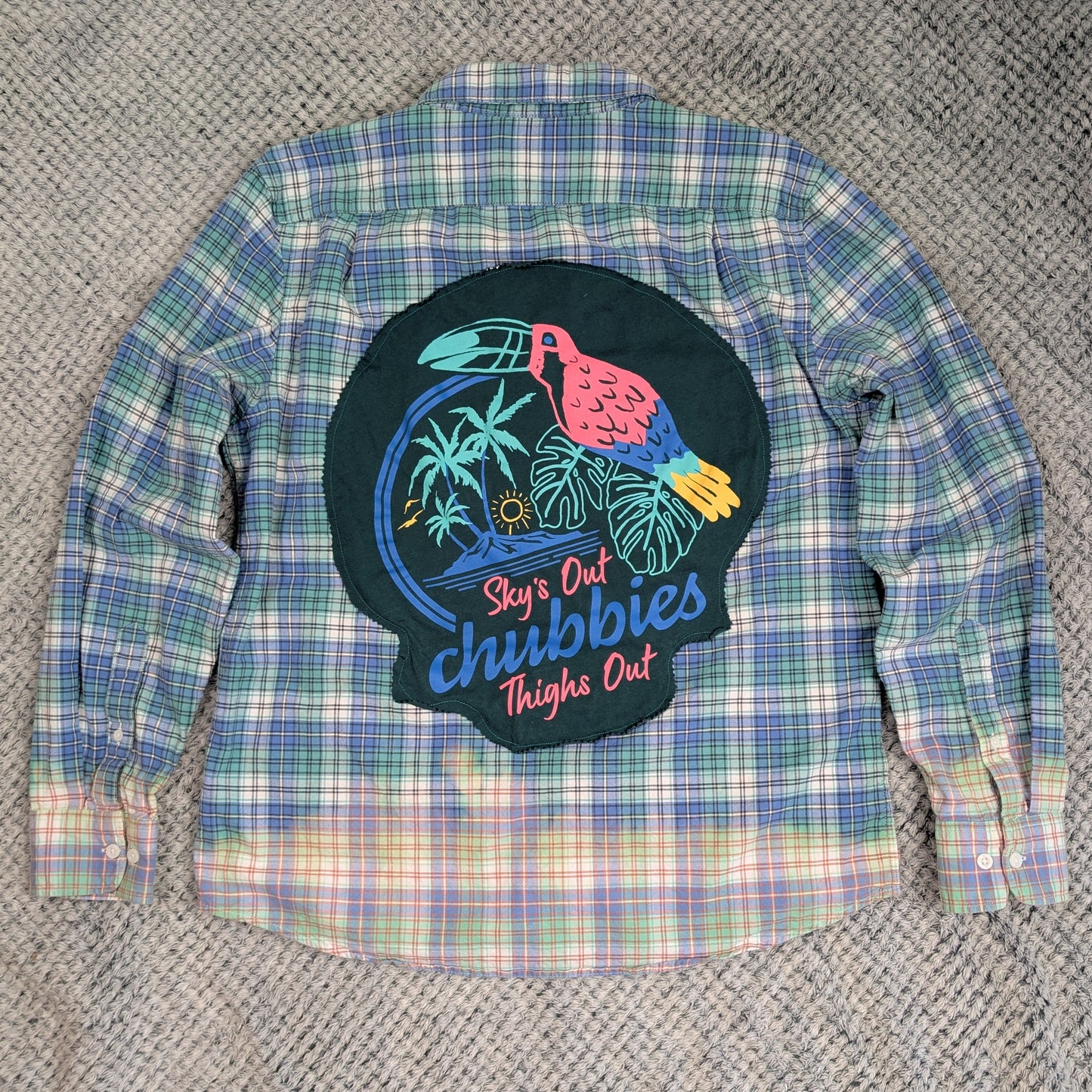 Plaid shirt with a colorful graphic patch on a textured surface