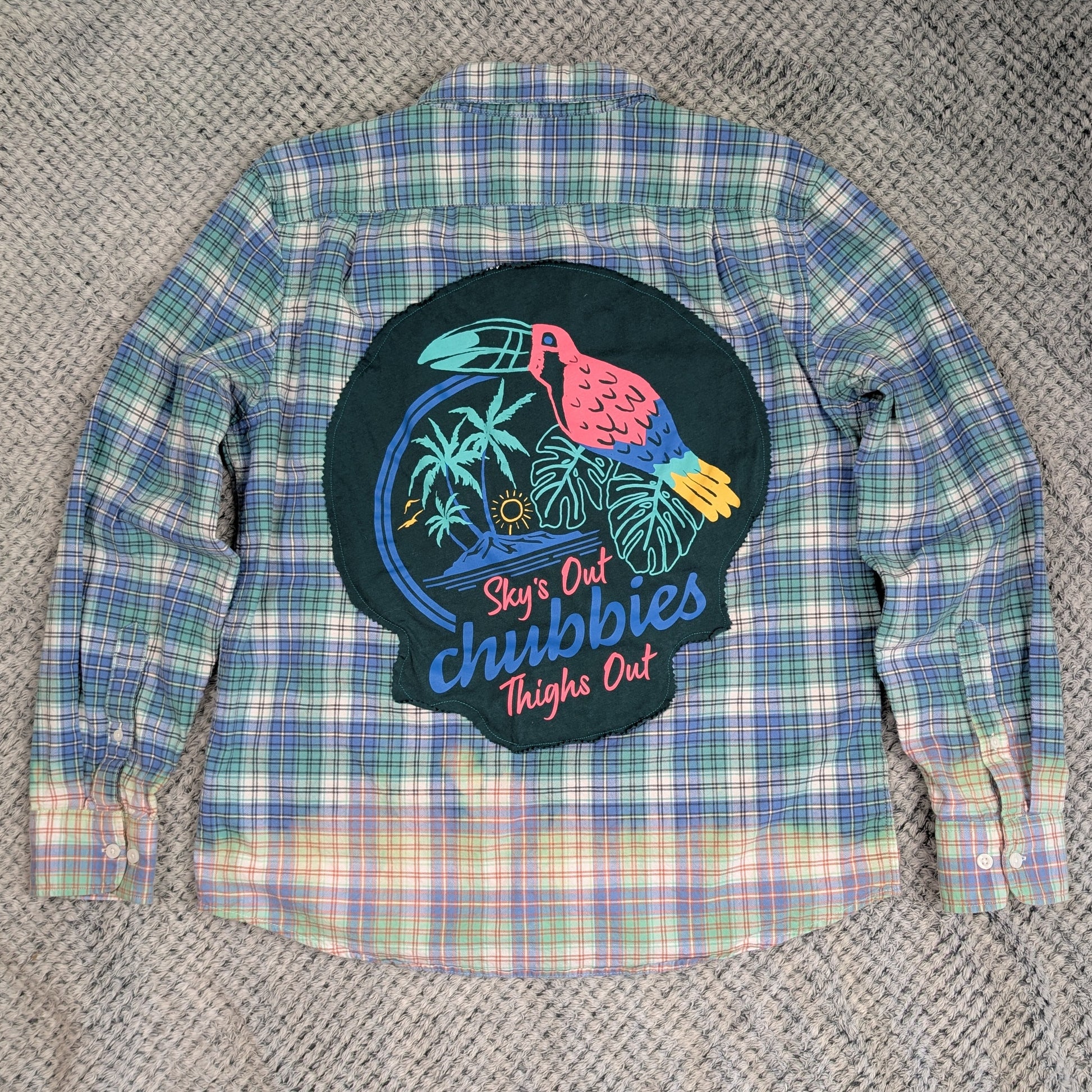 Plaid shirt with a colorful graphic patch on a textured surface