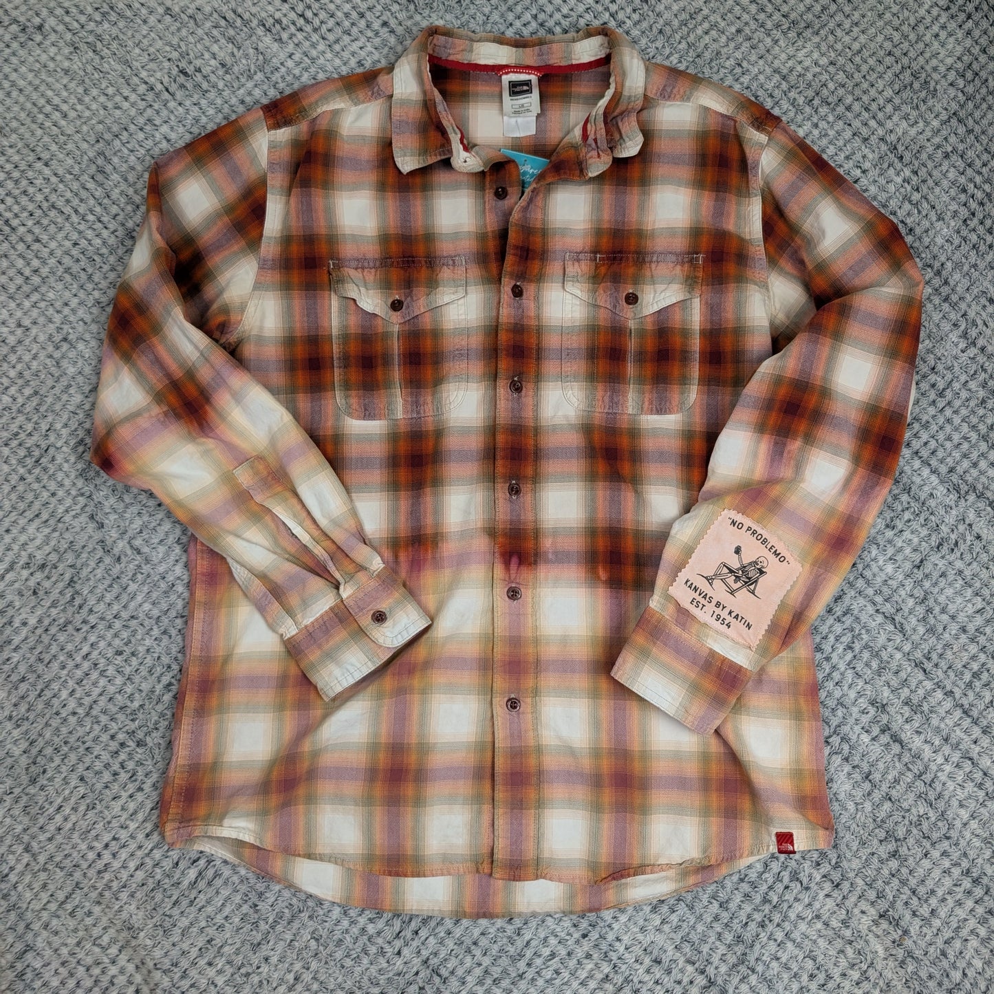 Plaid shirt with brand labels on a textured surface