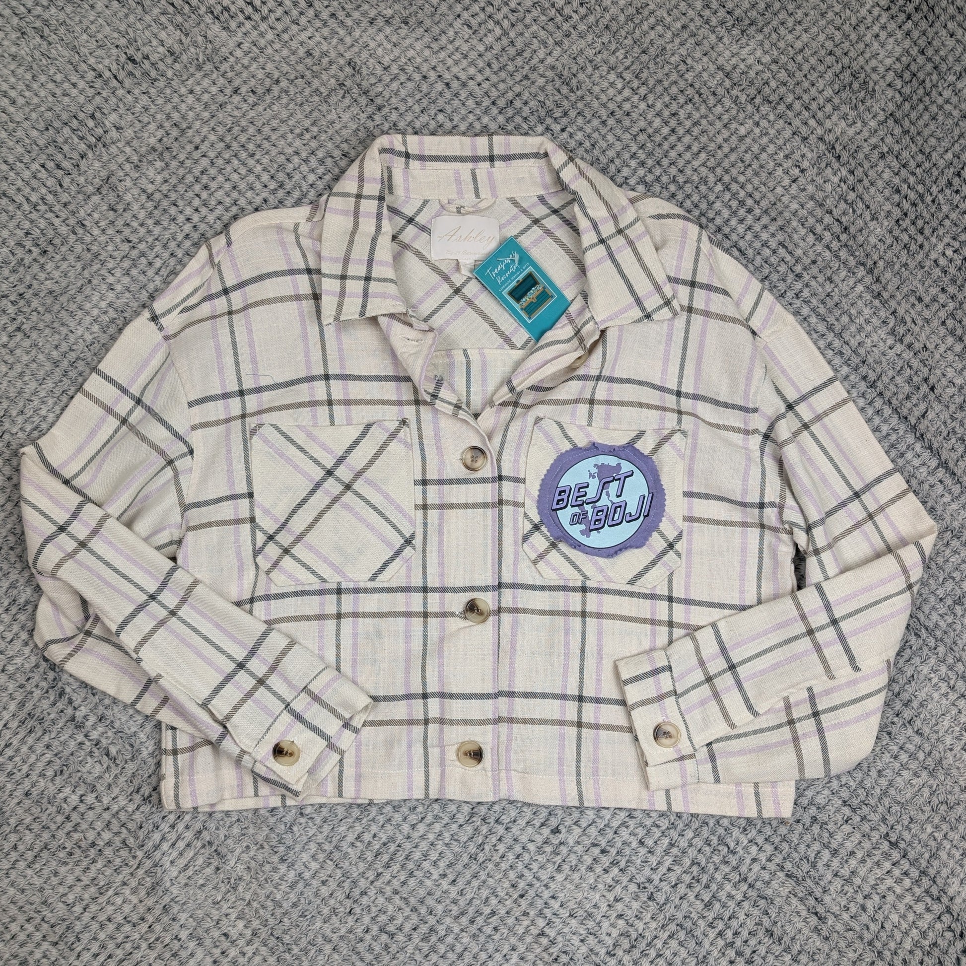 Plaid jacket with a brand logo on a textured gray surface