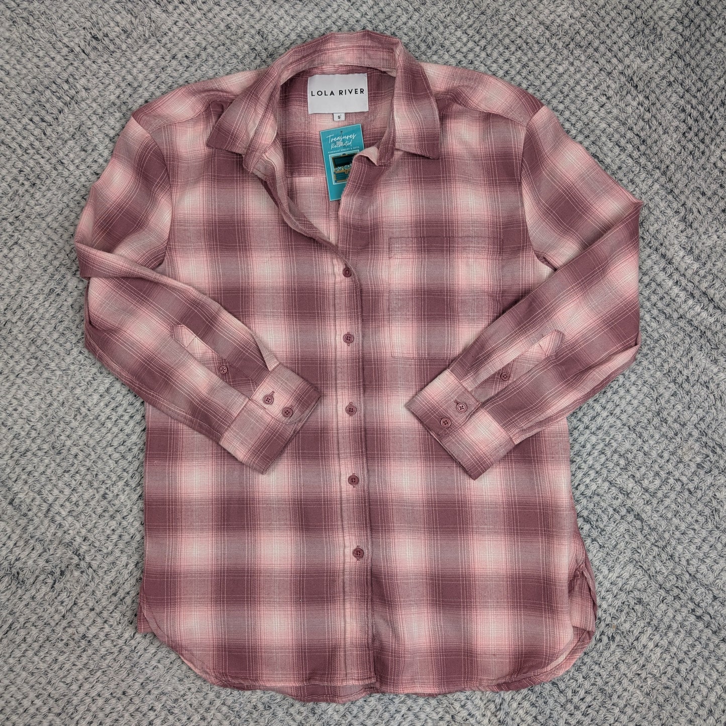 Pink plaid shirt on a textured gray surface