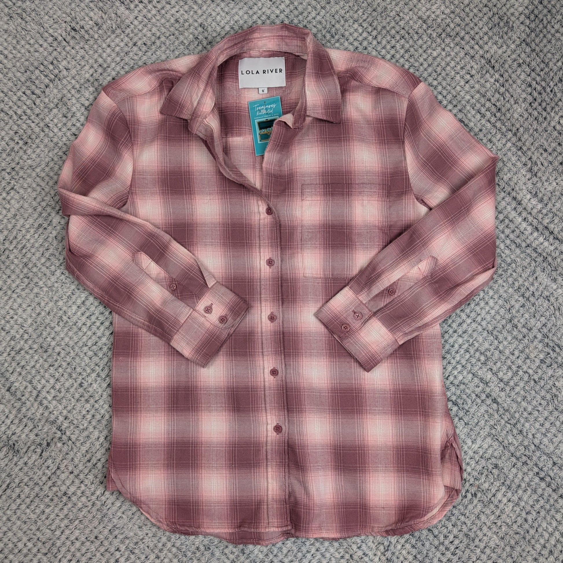 Pink plaid shirt on a textured gray surface