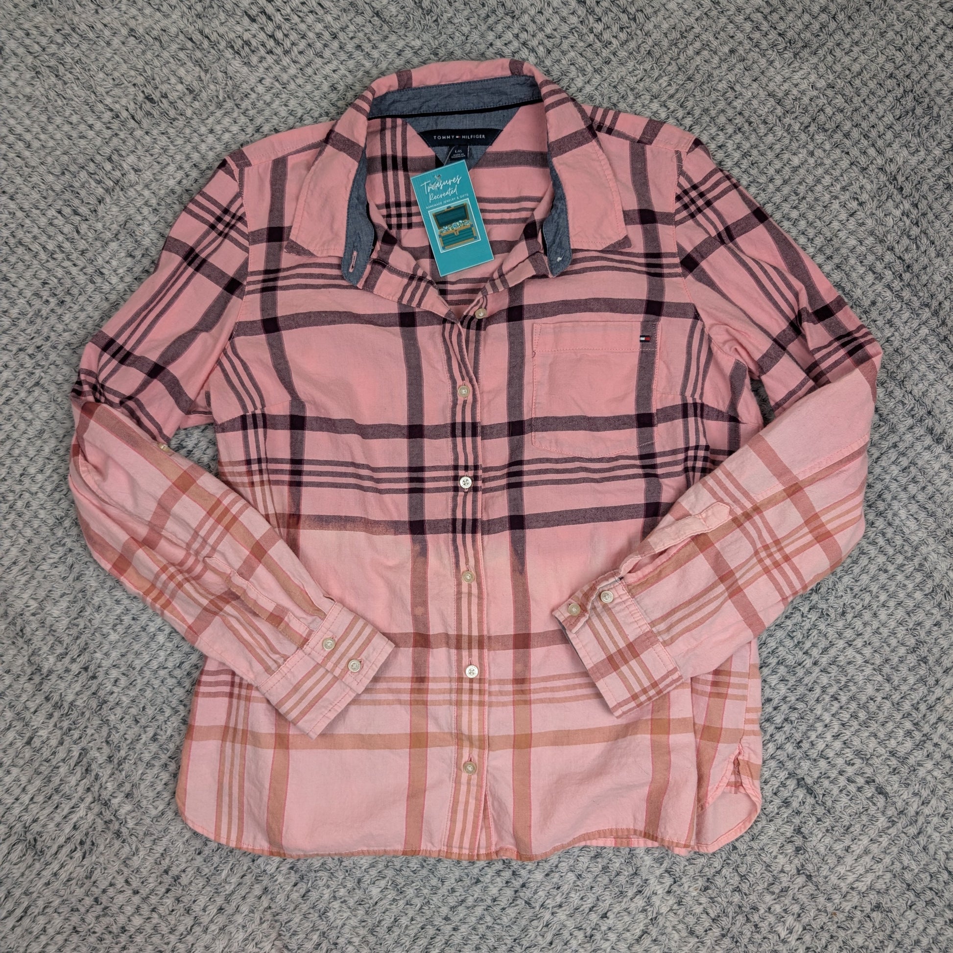 Pink plaid shirt with a tag on a textured gray surface