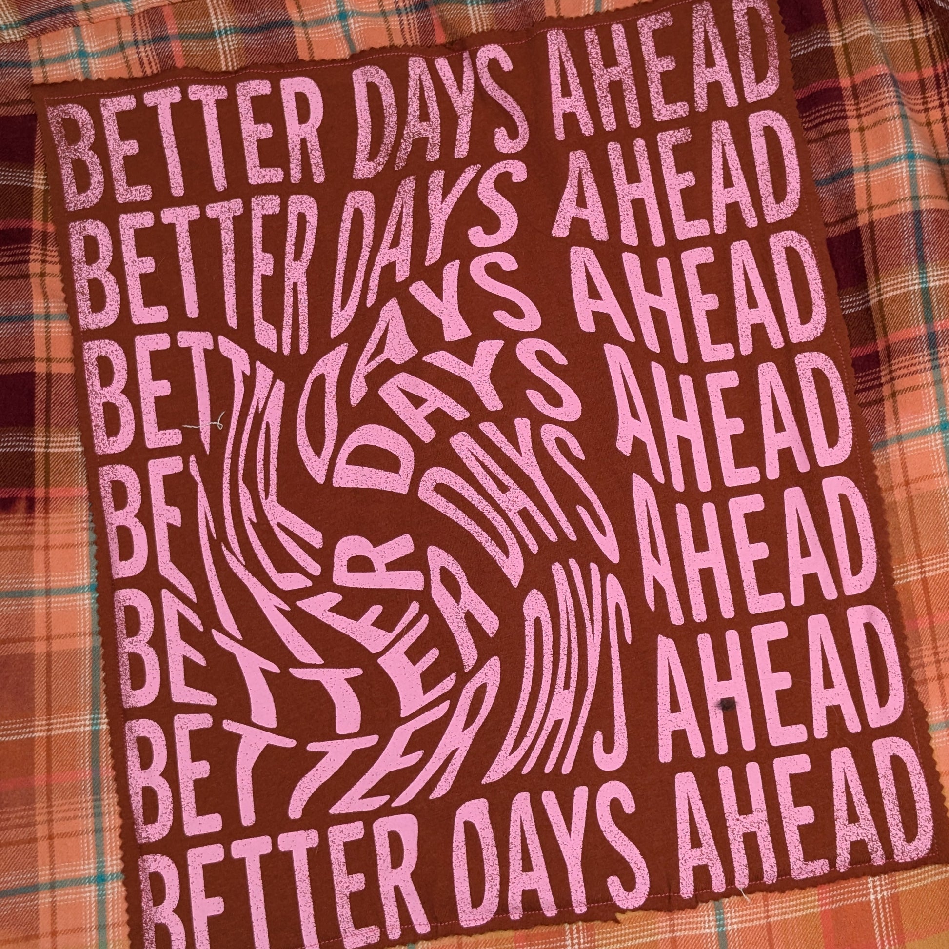 Text 'Better Days Ahead' on a plaid fabric background