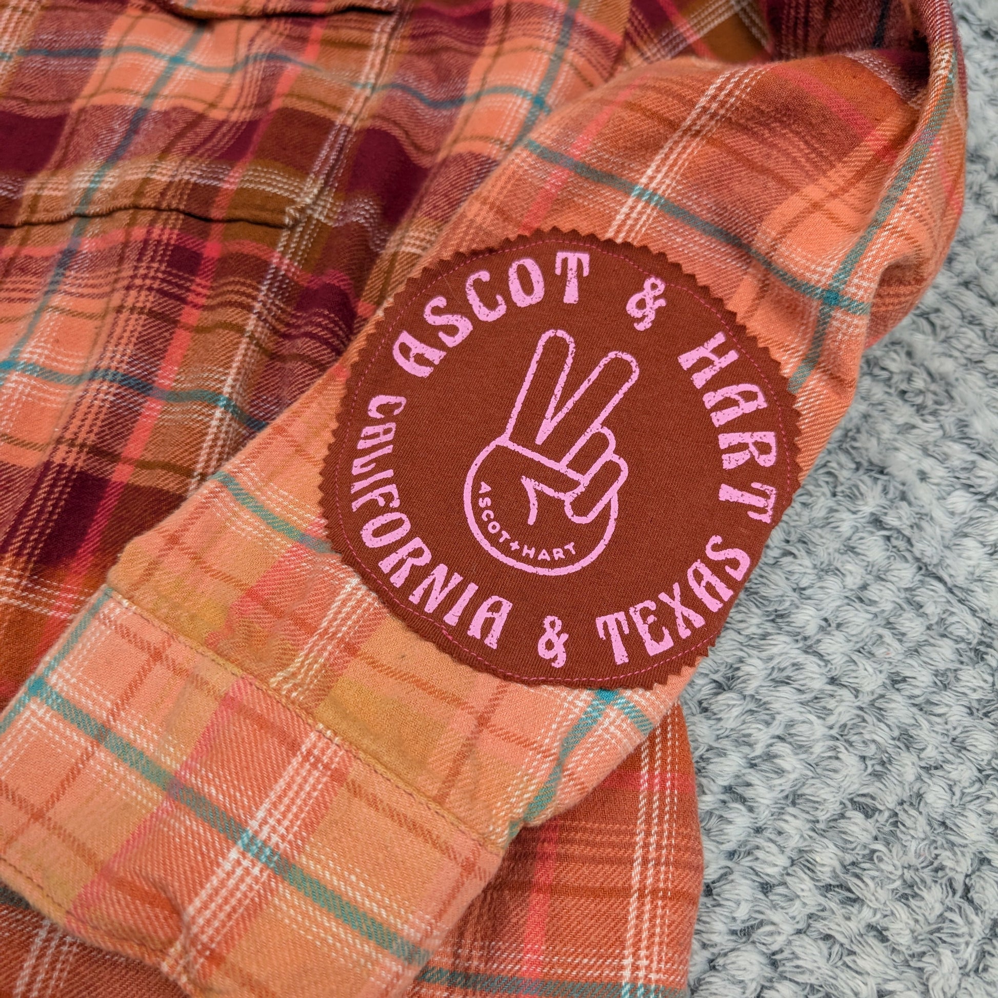 Plaid shirt with a visible brand patch on a textured surface