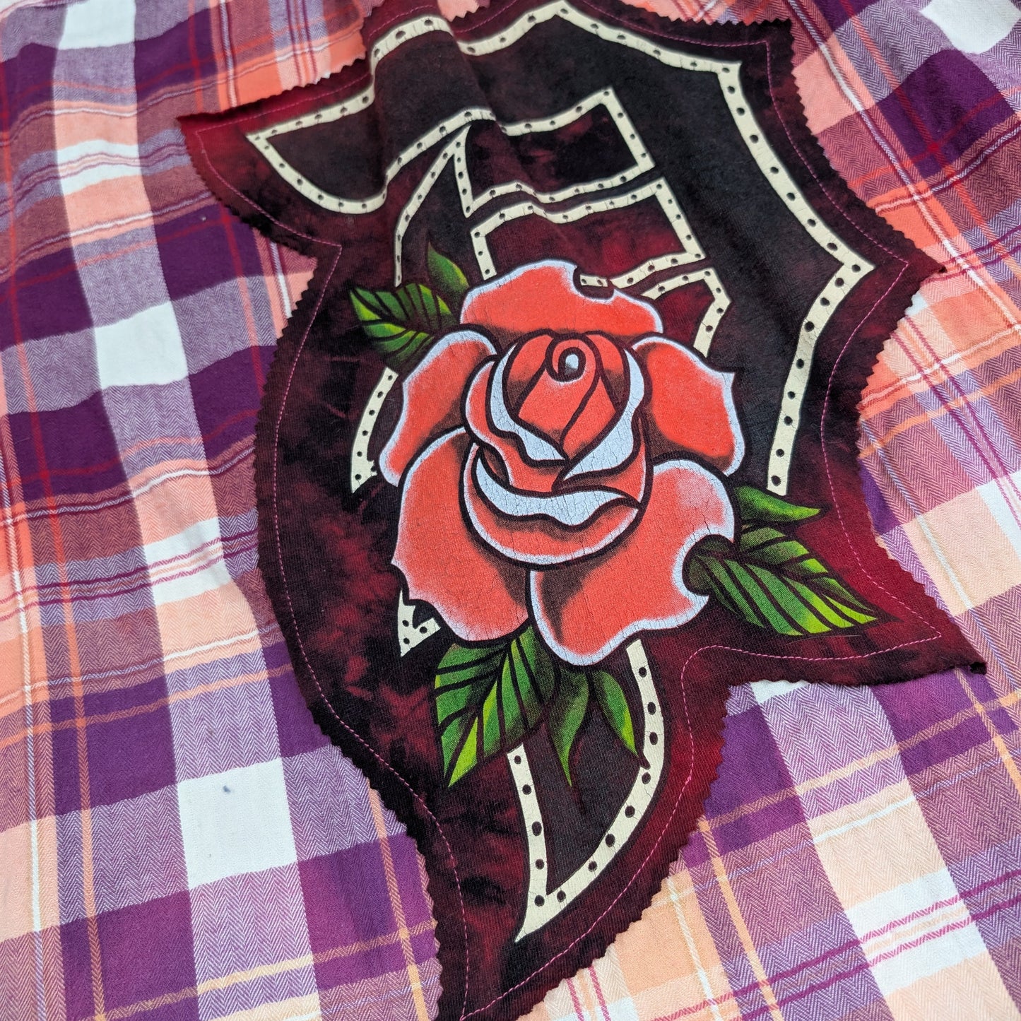 Decorative patch with a rose design on a plaid fabric background