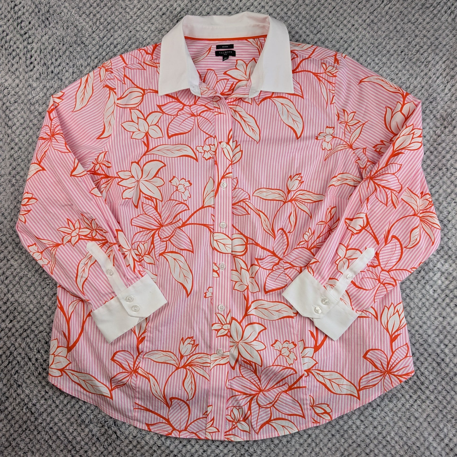 A pink and white striped long-sleeve button-up shirt with a coral orange and white floral print, laid flat on a gray textured carpet.