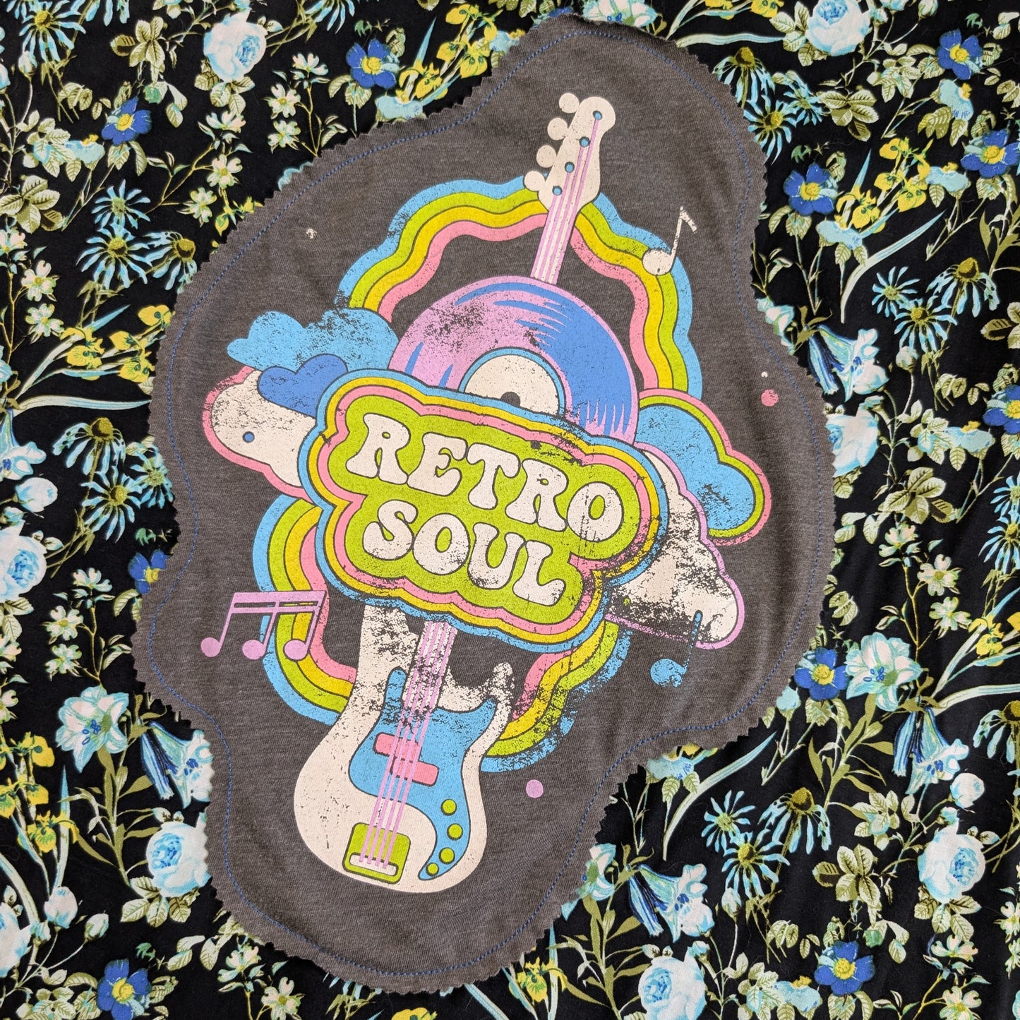 A distressed gray fabric patch with a colorful retro guitar and rainbow graphic reading 'RETRO SOUL,' laid flat on a black floral background.